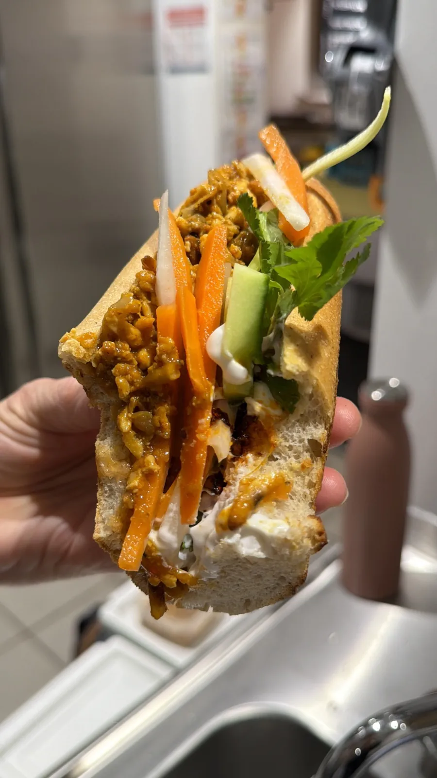 Et tværsnit af en Thai Banh Mi i baguette, fyldt med Sloppy Jo's Thai Filling, syltede gulerødder, kinaradise, agurk og frisk koriander