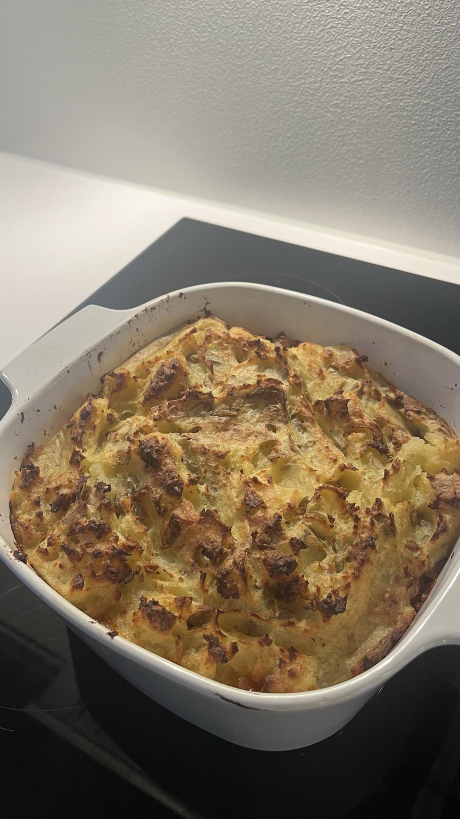 A golden-topped BBQ shepherd's pie fresh out of the oven in a white ceramic dish